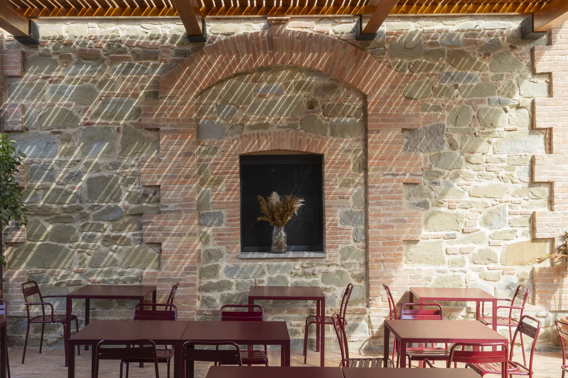Burgundy tables beneath the stone portico
